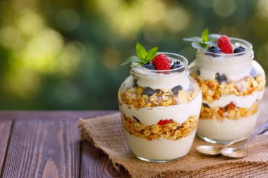 Yunan yoğurdu ve iki cam kavanozda böğürtlen.