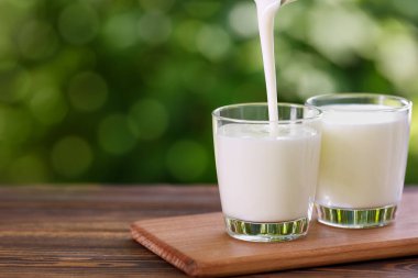 Yoğurt ahşap masada cama dökülüyor.