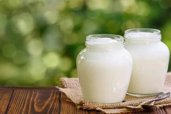 Greek yogurt in two glass jars on table outdoors — Stock Photo, Image