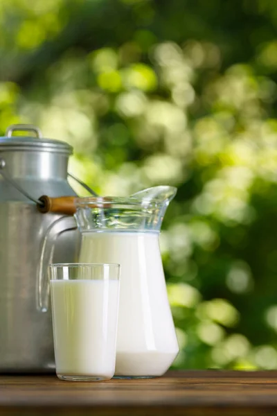 Молоко в стекле и кувшин с металлической банкой — стоковое фото