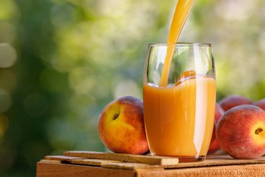 Taze şeftali suyu bardağa dökülüyor.