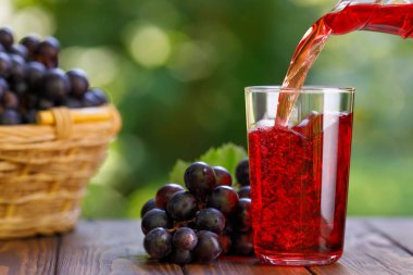 Üzüm suyu testiden bardağa dökülüyor.