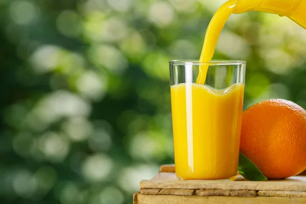 Färsk apelsinjuice som hälls i glas utomhus — Stockfoto