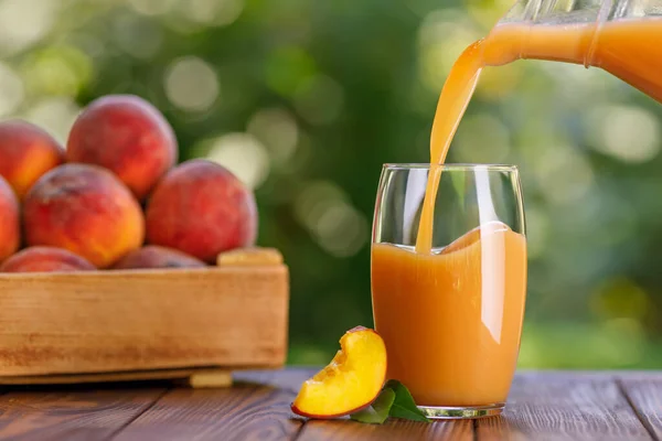 Frischer Pfirsichsaft, der im Freien in Glas gegossen wird — Stockfoto