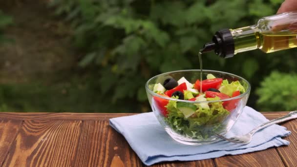 Olivolja som hälls ur flaskan i glasskål med färsk sallad — Stockvideo