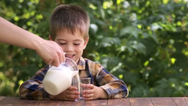 Mor hälla mjölk i glas för son — Stockvideo