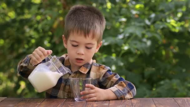 Malý nezávislý chlapec nalévání mléka do skla — Stock video