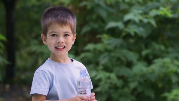 Liten pojke dricksvatten från plastflaska utomhus — Stockvideo