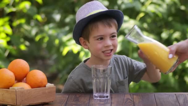 Ženská ruka nalévání čerstvé pomerančové šťávy pro dítě — Stock video