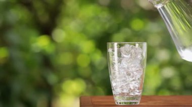 Bir sürahi buzla dolu bardağa dökülen su.