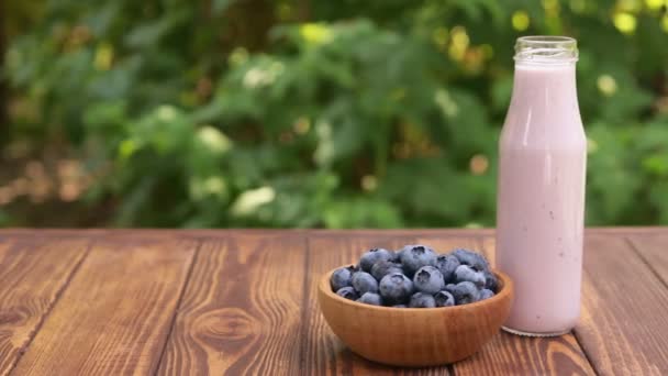 Blueberry σε μπολ και γιαούρτι ή smoothie σε γυάλινο μπουκάλι — Αρχείο Βίντεο