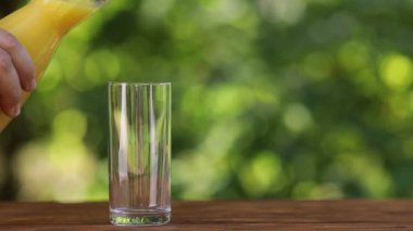 Erkek eli bardağa taze portakal suyu döküyor.