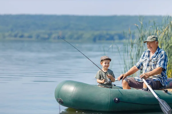 Grandfather with grandson together fishing from inflatable boat — Stock Photo, Image