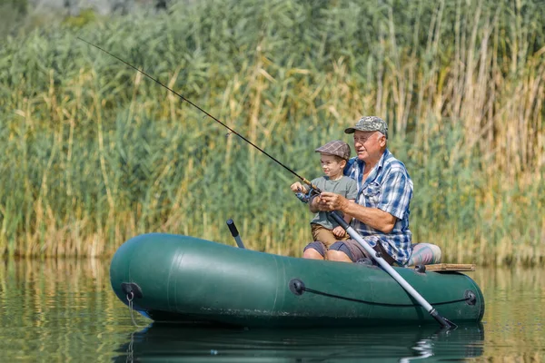 Grandfather with grandson together fishing from inflatable boat — Stock Photo, Image