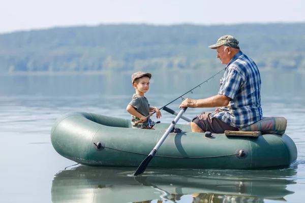 Grandfather with grandson together fishing from inflatable boat — Stock Photo, Image