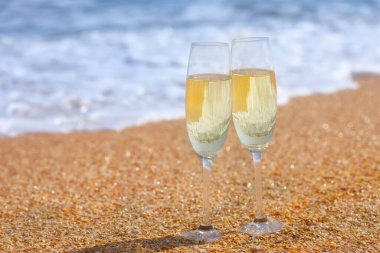 Deniz sahilinde iki kadeh şampanya.