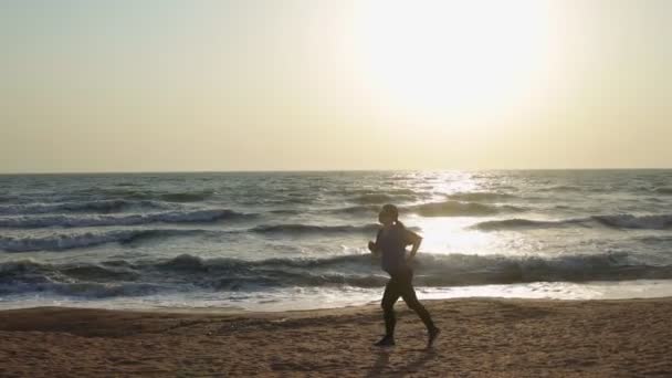 Mujer corriendo por la playa del mar y escuchando música — Vídeo de stock