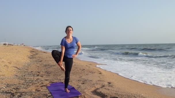 Kvinna utövar yoga vrikshasana pose på stranden — Stockvideo