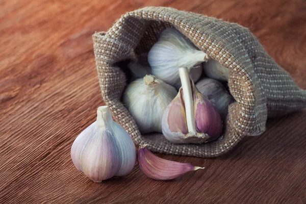 Garlics no saco em uma mesa de madeira — Fotografia de Stock