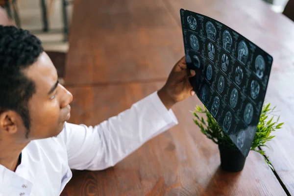 Top view of African American black male doctor in white coat analyzing history disease of patient