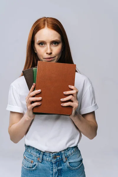 Upset sad young woman college student holding book and looking at camera on isolated background.