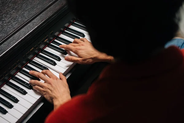 Top close-up view of hands of unrecognizable musician man playing on piano at home.