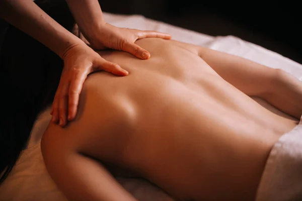 Young unrecognizable woman gets professional back massage in spa salon.