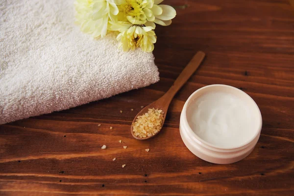 Crema de belleza de sal marina con flores y toallas sobre fondo de madera —  Fotos de Stock