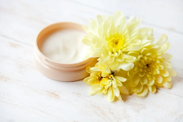 Crema con flor sobre mesa de madera —  Fotos de Stock