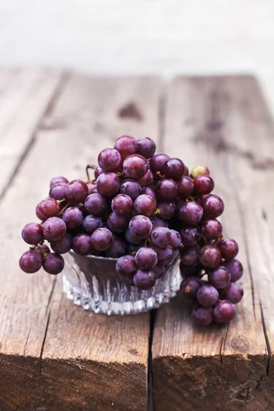 Świeże winogrona mokry ciemny niebieski z liści i winorośli na starym drewnianym stole w stylu rustykalnym — Zdjęcie stockowe