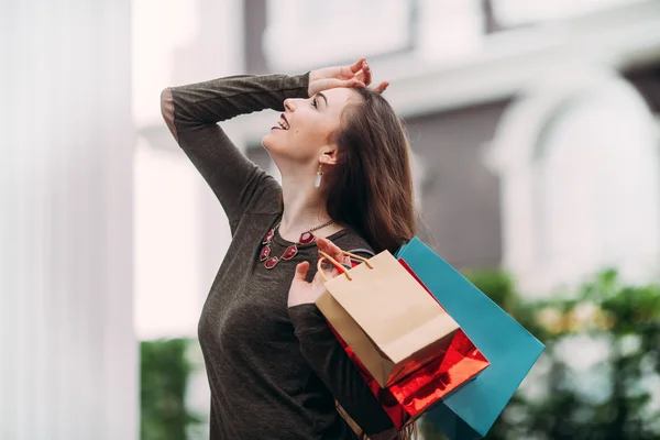 Hermosa mujer con bolsas de compras sonríe y se ve feliz —  Fotos de Stock