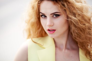 Bir şehir sokak poz güzel genç bayan. Kameraya bakarak bir sarı ceket giymiş.