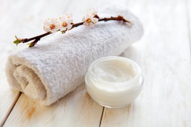 Beyaz ahşap masa üzerinde kayısı çiçeği ile yüz kremi