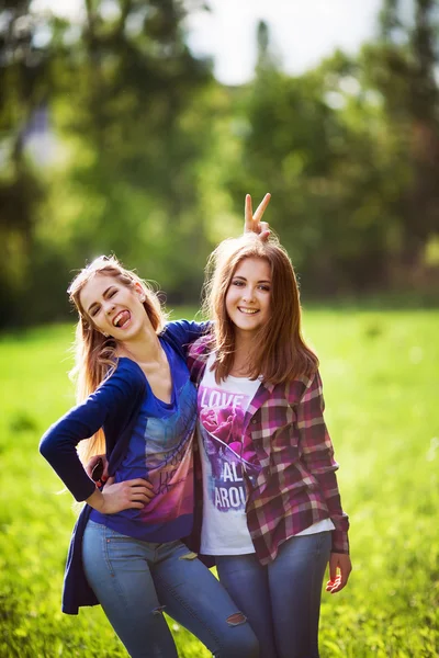 Dos mujeres jóvenes abrazan y se ríen en el parque — Foto de Stock