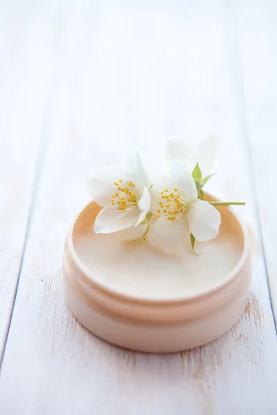 Crema con flor de jazmín sobre mesa de madera blanca —  Fotos de Stock