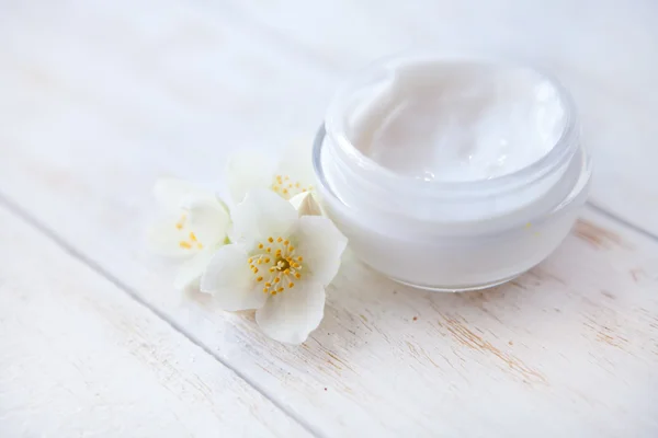 Crema facial con flor de jazmín sobre mesa de madera blanca —  Fotos de Stock