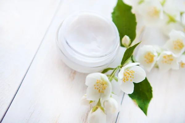 Maceta de crema de belleza con pétalos de flores sobre mesa de madera blanca —  Fotos de Stock