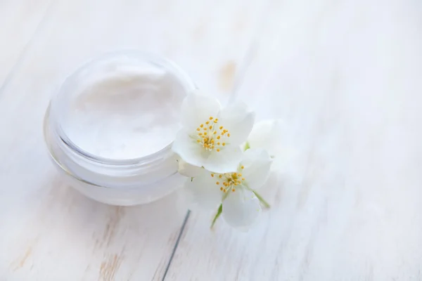 Maceta de crema de belleza con flor de jazmín sobre mesa de madera blanca. De cerca. —  Fotos de Stock