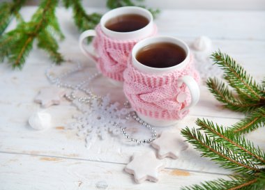 Noel ağacı, kurabiye ve örme bardak tutucu beyaz tahta masada sıcak çay