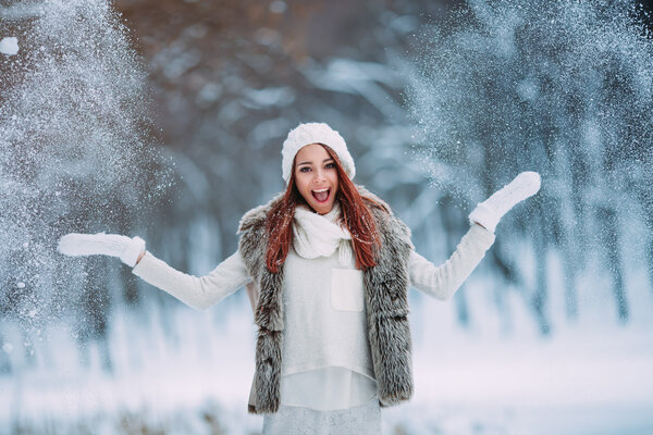 Happy young woman plays with a snow outdoor. Winter day