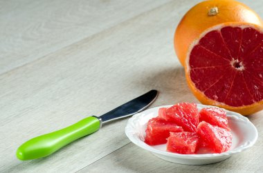 Greyfurt dilim bir tabak ve ahşap masa üzerinde bir bıçak