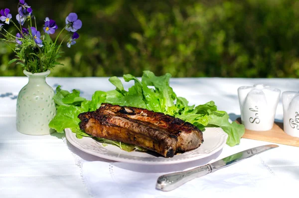 ステーキと庭のテーブルの上の皿にレタス — ストック写真