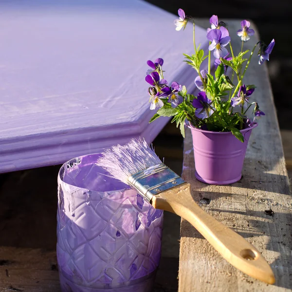 Purple paint in a jar and brush on the background of painted boa