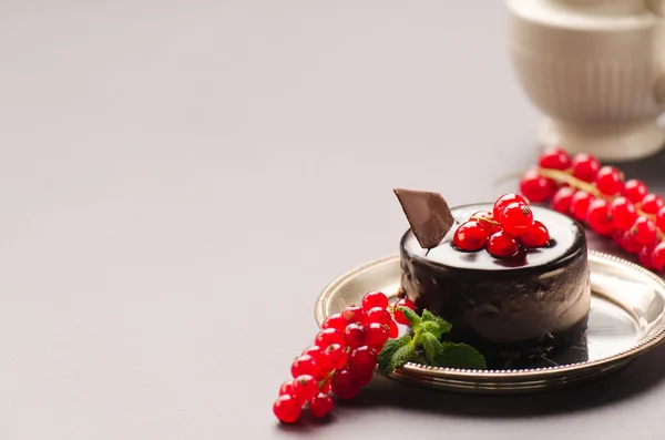Pastel de chocolate con grosella roja sobre fondo gris — Foto de Stock