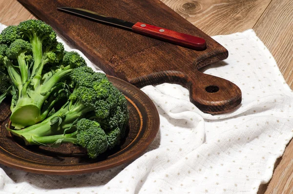 Broccoli pe o placă de lut, o placă de tăiere și un cuțit — Fotografie, imagine de stoc