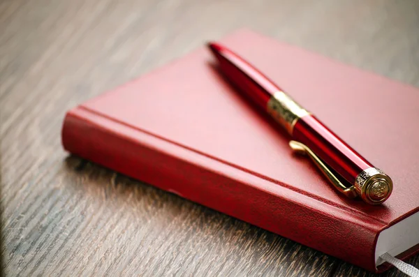 Kırmızı defter ve masada kırmızı lüks kalem