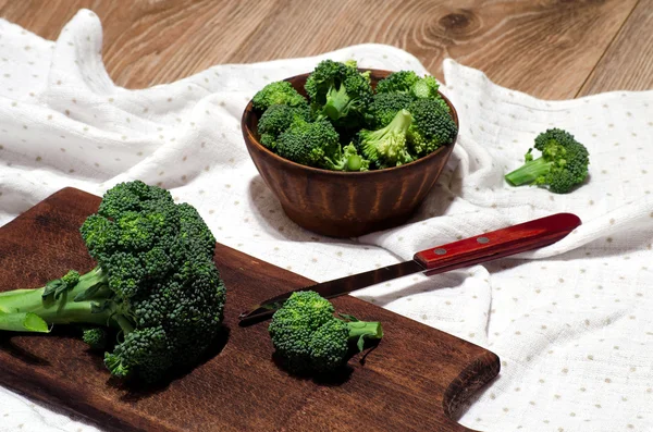 Broccoli su un piatto di argilla, un tagliere e un coltello — Foto Stock