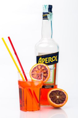 Glass of light drink and ice cube with bottle of Aperol
