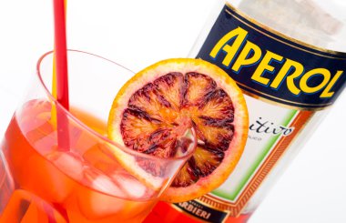 Glass of light drink and ice cube with bottle of Aperol