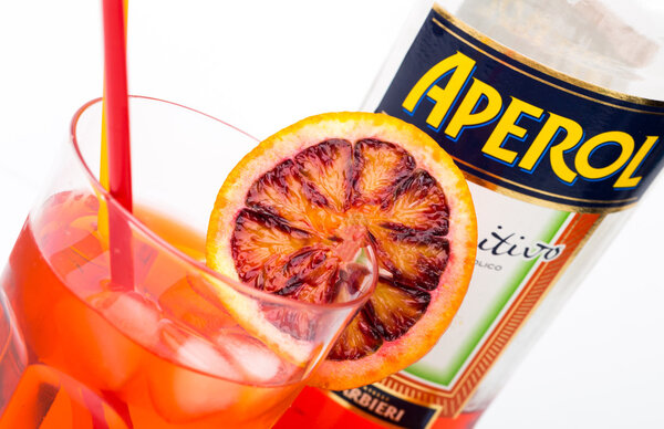 Glass of light drink and ice cube with bottle of Aperol